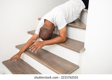 A young man faints and collapses on the stairs of the house. He was injured in an accident and fell down the stairs. He was alone in the house not being helped by anyone. Broken bone - Shutterstock ID 2215762531