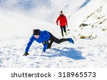 Young man falling while jogging outside in sunny winter mountains