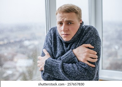 Young Man Feeling Cold In Flat Near The Window