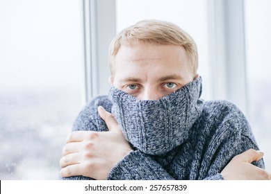 Young Man Feeling Cold In Flat Near The Window