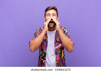 Young Man Feeling Happy, Excited And Positive, Giving A Big Shout Out With Hands Next To Mouth, Calling Out