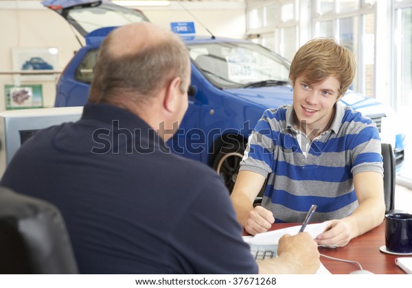 Young man\
filling in paperwork in car\
showroom
