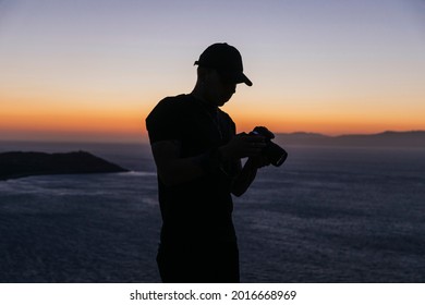 Young Man Filmmaker At The Top Of A Hill At Sunset Time