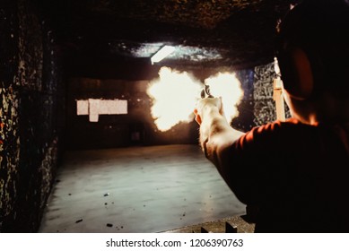 Young Man Firing A Gun At A Shooting Range In The Precise Moment Of Muzzle Flash