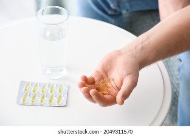 Young Man With Fish Oil Pills At Home, Closeup