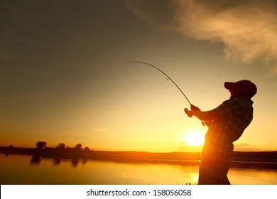 Young Man Fishing From A Boat At Sunset