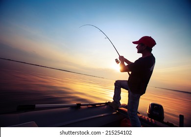 Young man fishing from the boat at sunset - Powered by Shutterstock