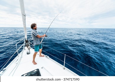 Young man fishing in open sea from sail boat