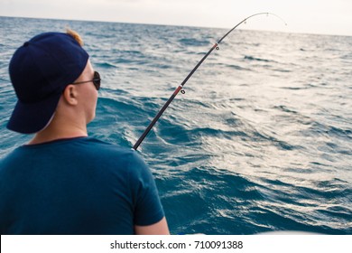 Young Man Fishing In Open Sea On Sunset