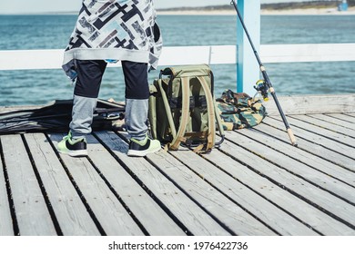 Young man with fishing rod on the Baltic sea pier. People leisure hobby concept.