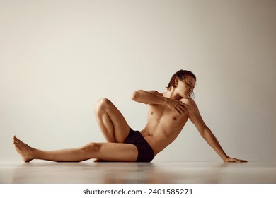 Young man with fit, healthy, muscular body sitting on floor in underwear against grey studio background. Concept of men's beauty, health, body care, sportive lifestyle - Powered by Shutterstock