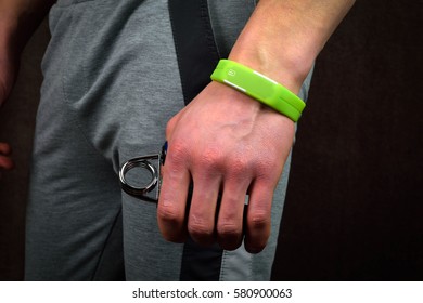 Young man with fitness bracelet tracker on a hand on a dark background