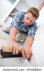 Young Man Fitting Carefully A Roll Of Carpet