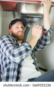 Young Man Fixing A Leaky Pipe Under The Sink