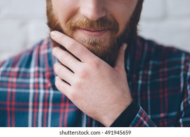 Young Man In A Flannel Shirt Touches With Hand His Beard