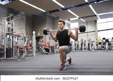 Young Man Flexing Muscles With Barbell In Gym