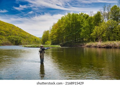 Young man fly fishing on a river from on sunny day - Powered by Shutterstock