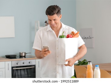 Young Man With Food In Bag And Mobile Phone At Home