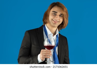 A Young Man In A Formal Suit With A Tie Holds A Glass Of Wine At An Office Party Or Prom. A 21 Year Old Guy Drinks Alcohol.