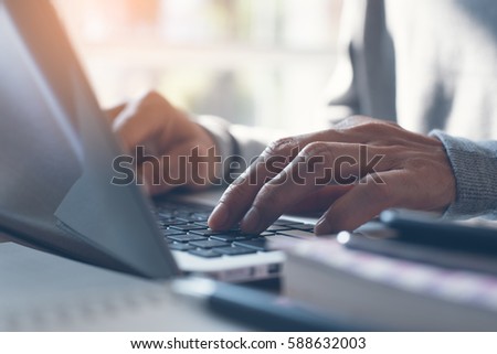 Young man or freelancer using laptop computer, searching web with morning light, browsing internet information, working from home concept, close up