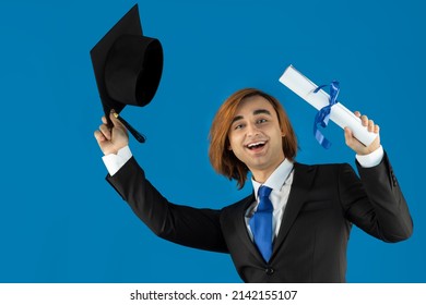 Young Man Fresh Graduate Wearing Graduation Caps With Tassel Formal Suit, And Tie. Portrait Of Guy Holding Blue Ribbon Diploma, Certificate.