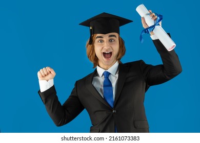 Young Man Fresh Graduate Wearing Graduation Caps With Tassel Formal Suit, And Tie. Portrait Of Guy Holding Blue Ribbon Diploma, Certificate.
