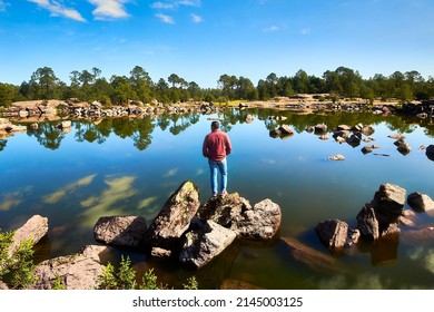 young man in front of a lake with a lot of rocks and forest in the background in mexiquillo durango, sierra madre occidental 