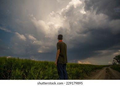 Young man in front of a storm cloud in the field