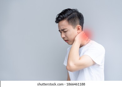 Young man is frowning painfully with hand over his neck