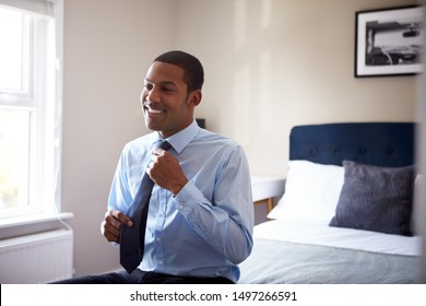 Young Man Getting Dressed In Bedroom For First Day At Work In Office