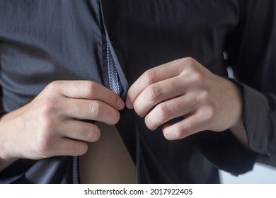 The Young Man Is Getting Dressed.The Concept Of Fashionable Clothing Is A Close-up Of A Man Getting Dressed And Buttoning A Black Shirt