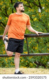 Young man getting fit before summer. Man doing a stretching routine. Young man doing sports in the park. Man doing his morning workout routine. Person getting ready before running