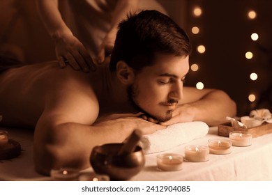 Young man getting massage in dark spa salon, closeup - Powered by Shutterstock