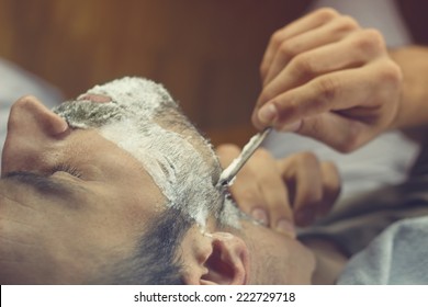 Young Man Getting An Old-fashioned Shave At The Barber Shop. Closeup, Retro Styled Imagery