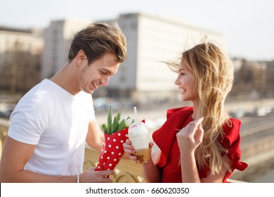 Young man give bouquet to woman in red dress at first date