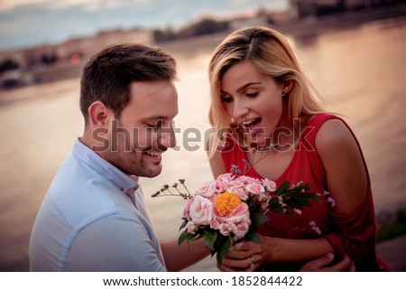 Young man is giving bouquet of flowers to his girlfriend.