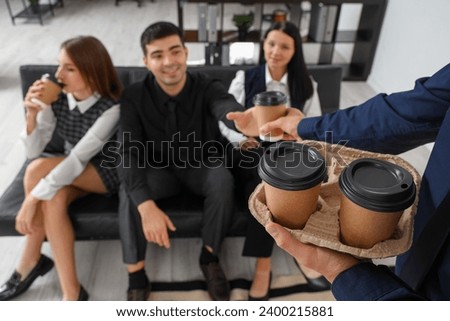 Young man giving coffee to his colleagues in office, closeup