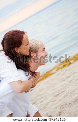 Young man giving his girlfriend a piggy back on the beach