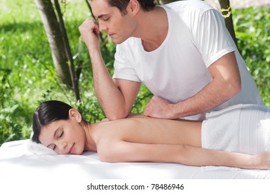 Young man giving massage elbow to a beautiful woman on back - Powered by Shutterstock