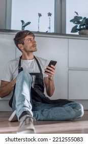 Young Man With Glass Of Water Reading SMS On His Phone