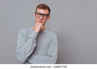 Young man in glasses. hand near the face. looking at camera. isolated gray background - Shutterstock ID 520857730