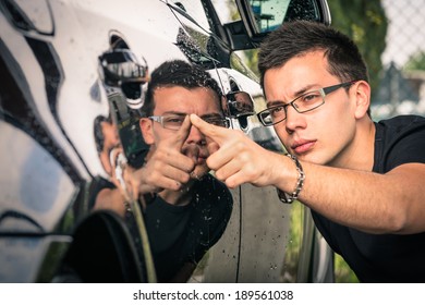 Young man with glasses inspecting a luxury car before a second hand trade