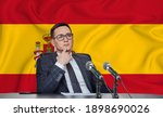 Young man in glasses and a jacket at an international meeting or press conference negotiations, on the background of the flag Spain