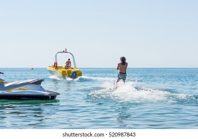 Young Man Glides On Water Skiing On The Waves On The Sea, Ocean. Healthy Lifestyle. Positive Human Emotions, Feelings, Joy. Funny Cute Boy Making Vacations And Enjoying Summer.