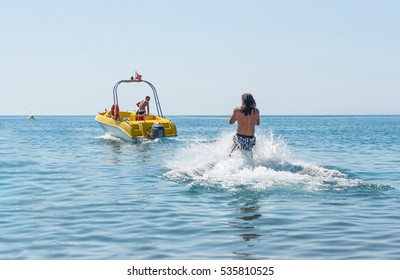 Young Man Glides On Water Skiing On The Waves On The Sea, Ocean. Healthy Lifestyle. Positive Human Emotions, Joy. Funny Cute Boy Making Vacations And Enjoying Summer. Spring And Summer Holidays.