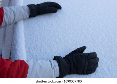 Young Man With Gloves Picking Up Snow From A Car Window To Make A Snowball On A Cold Winter Day With Copy Space