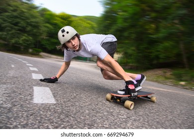 Young man is going to slide, slide with sparks on a longboard on the asphalt