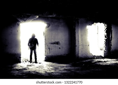 Young Man Goint To Bright Light. Abandoned Unfinished Construction And A Young Man Going To The Doorway. Bright Light Coming Through A Doorway.