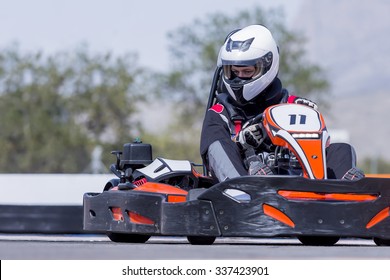 young man go-kart pilot is racing a race in an outdoor go karting circuit - focus on the helmet