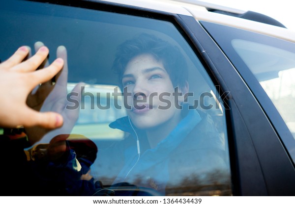 young man gold his hand on a car window and say\
goodbye to a friend